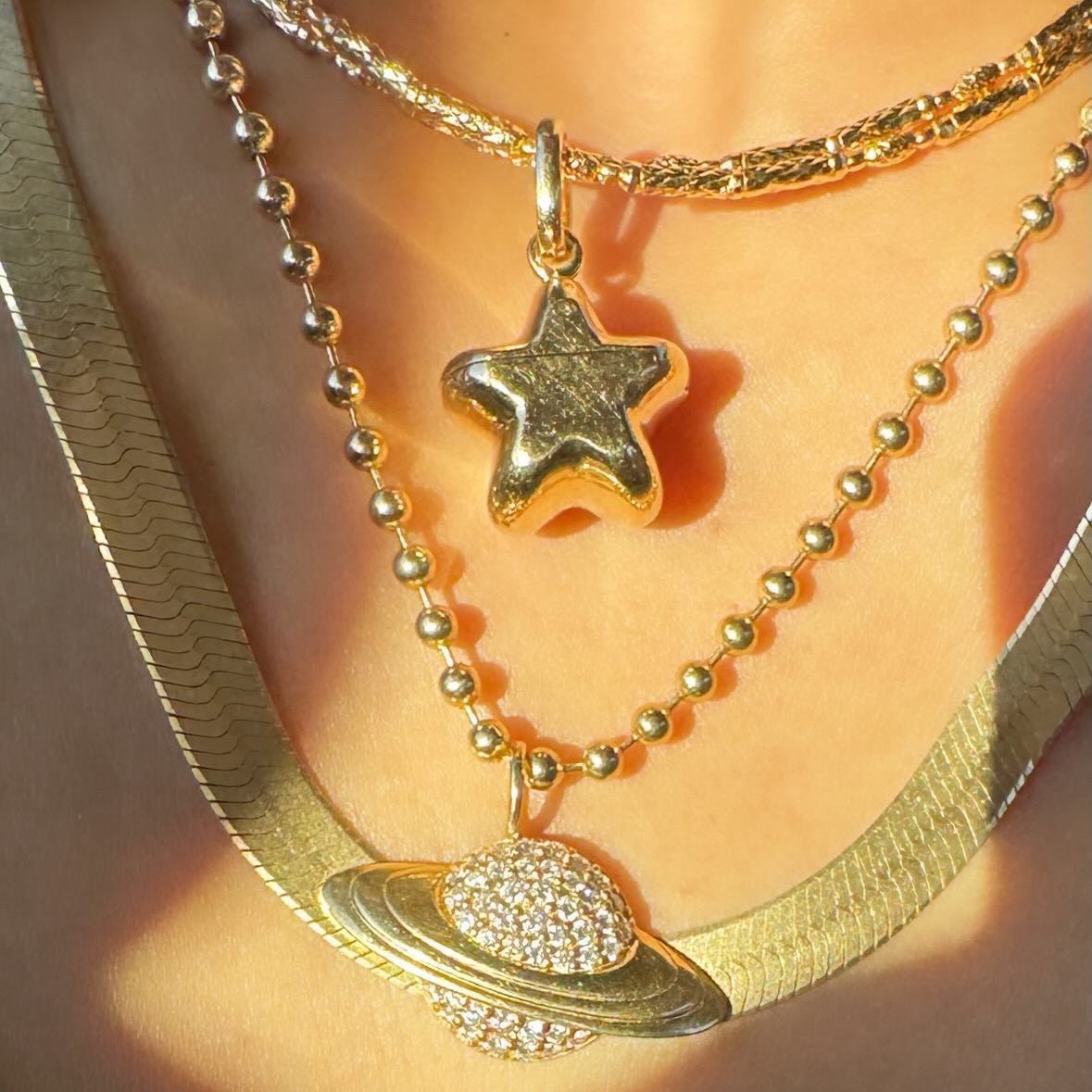 Person wearing multiple gold chains and pendants including a magnetic rope style gold chain
