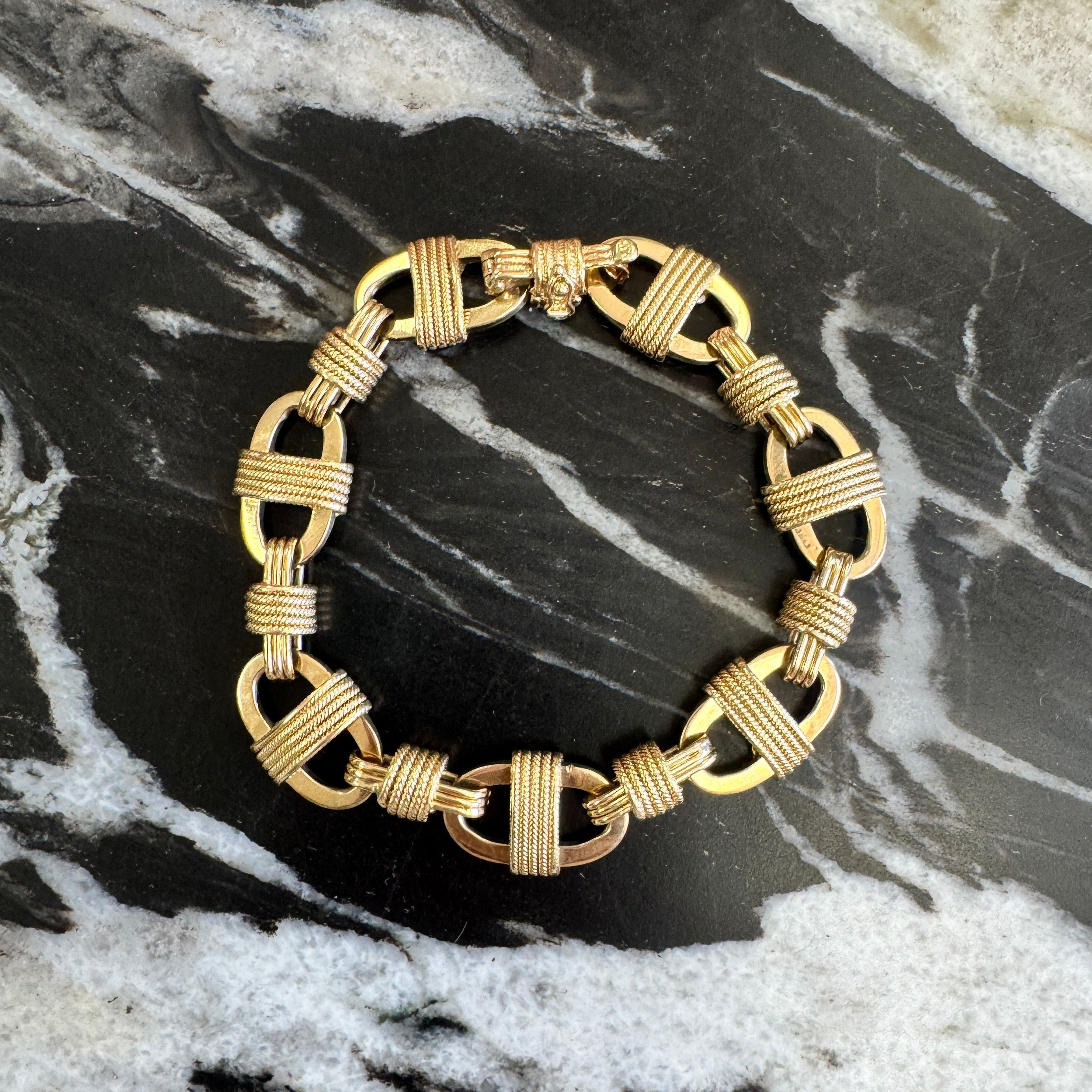 Gold bracelet on a black and white marble surface