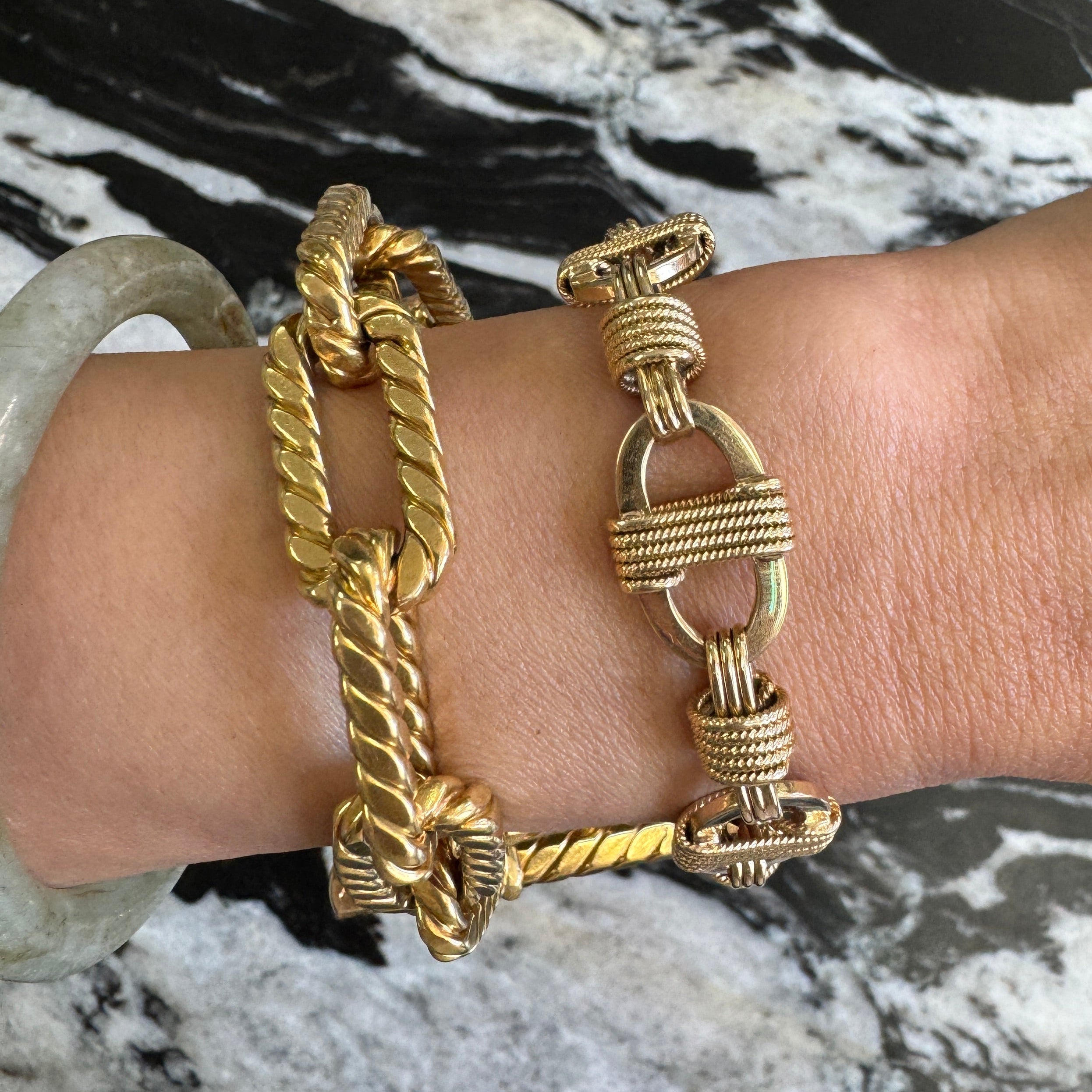Gold bracelets on a wrist with a marble background