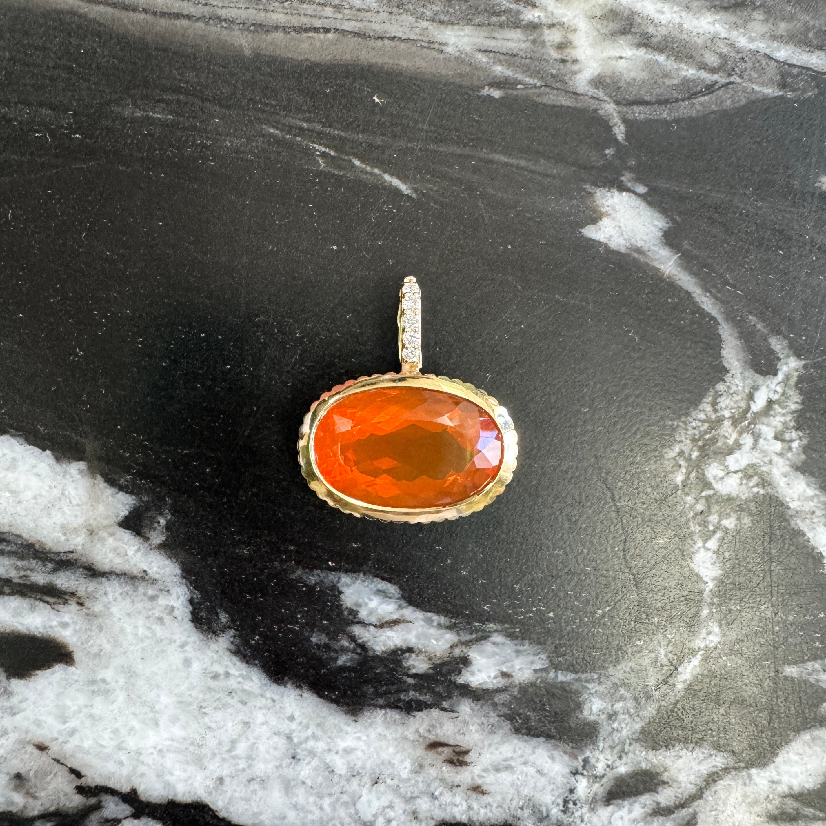 Pendant with a red orange stone on a textured black and white background