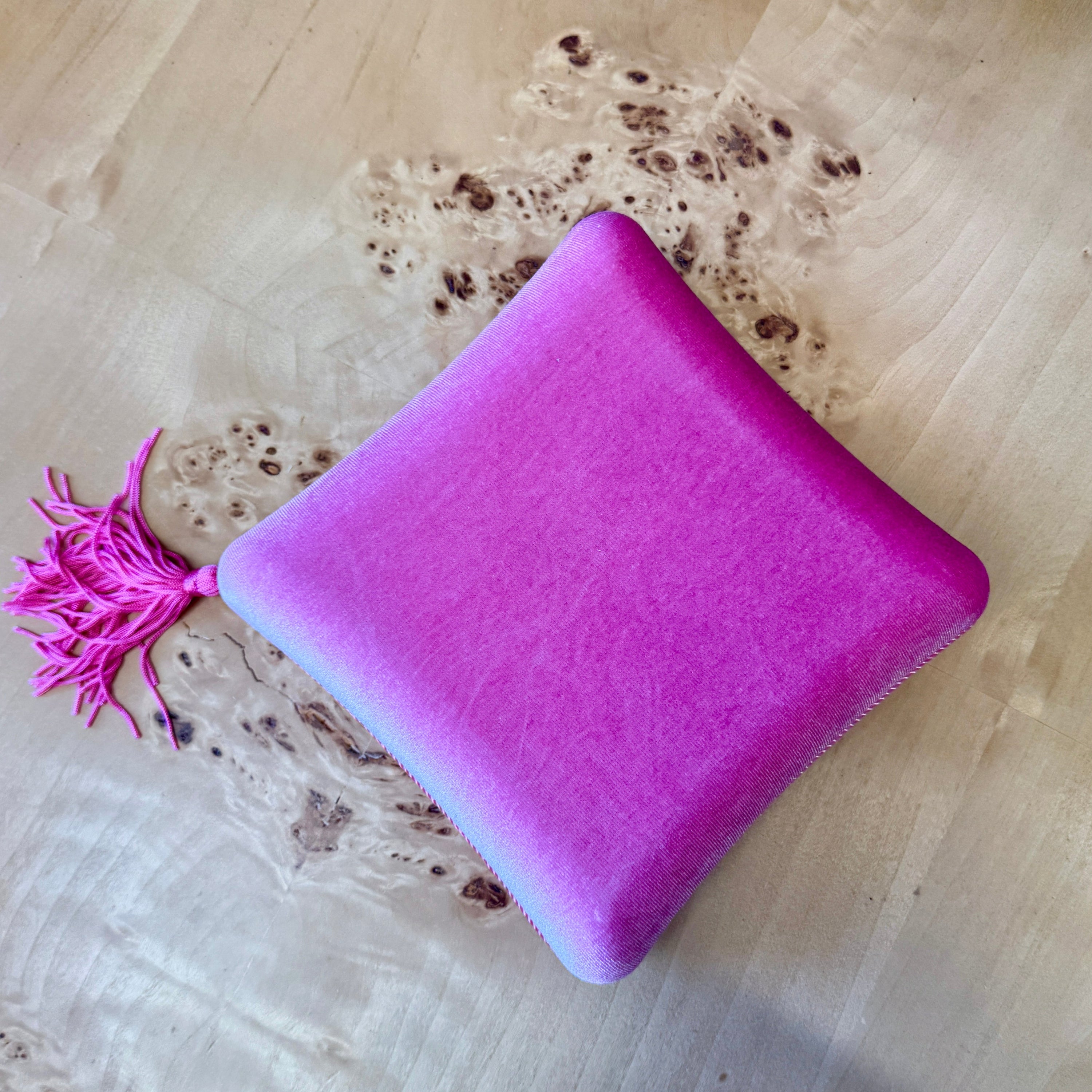 pink cushion with a pink tassel on a wooden surface