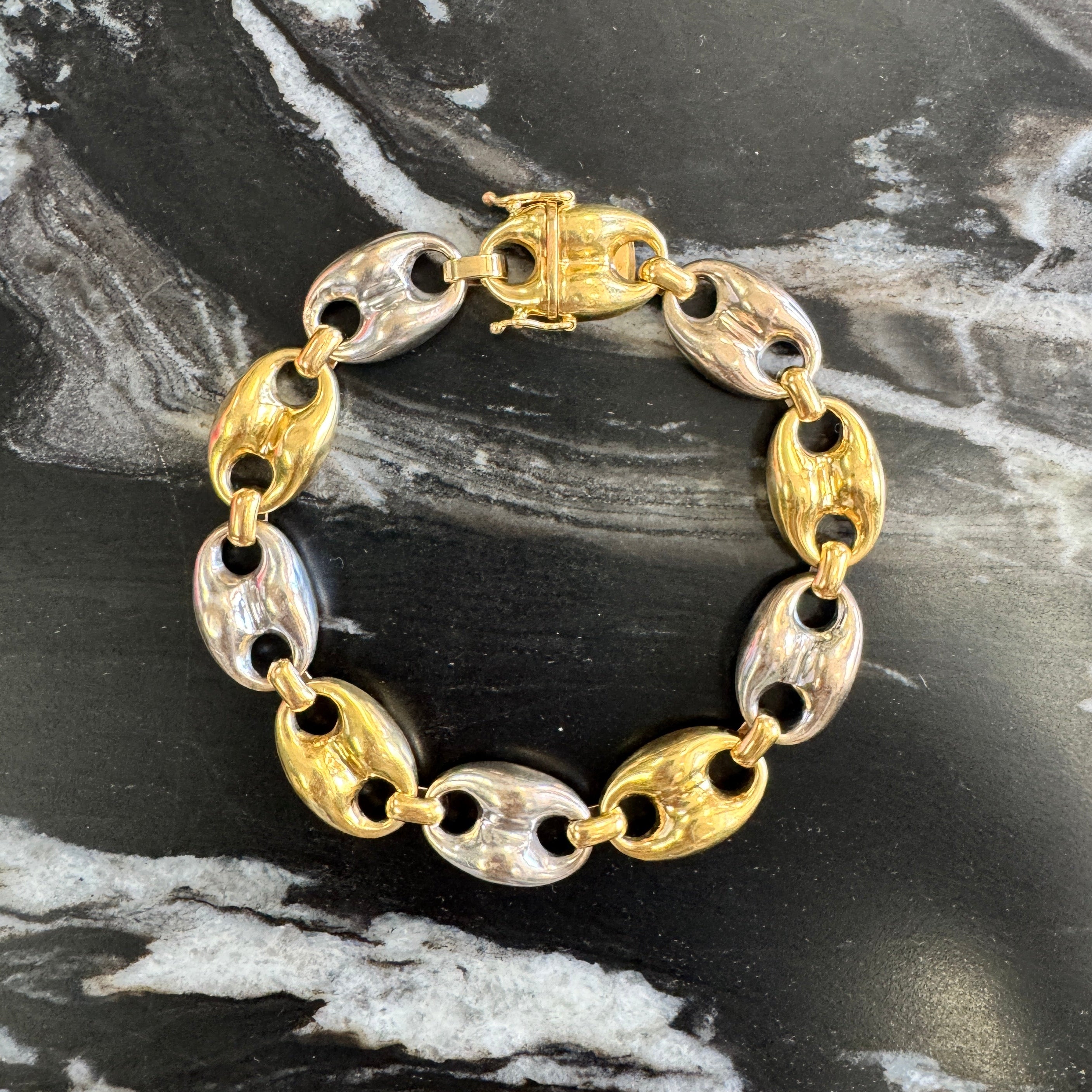 Gold and white gold bracelet on a black and white marble surface