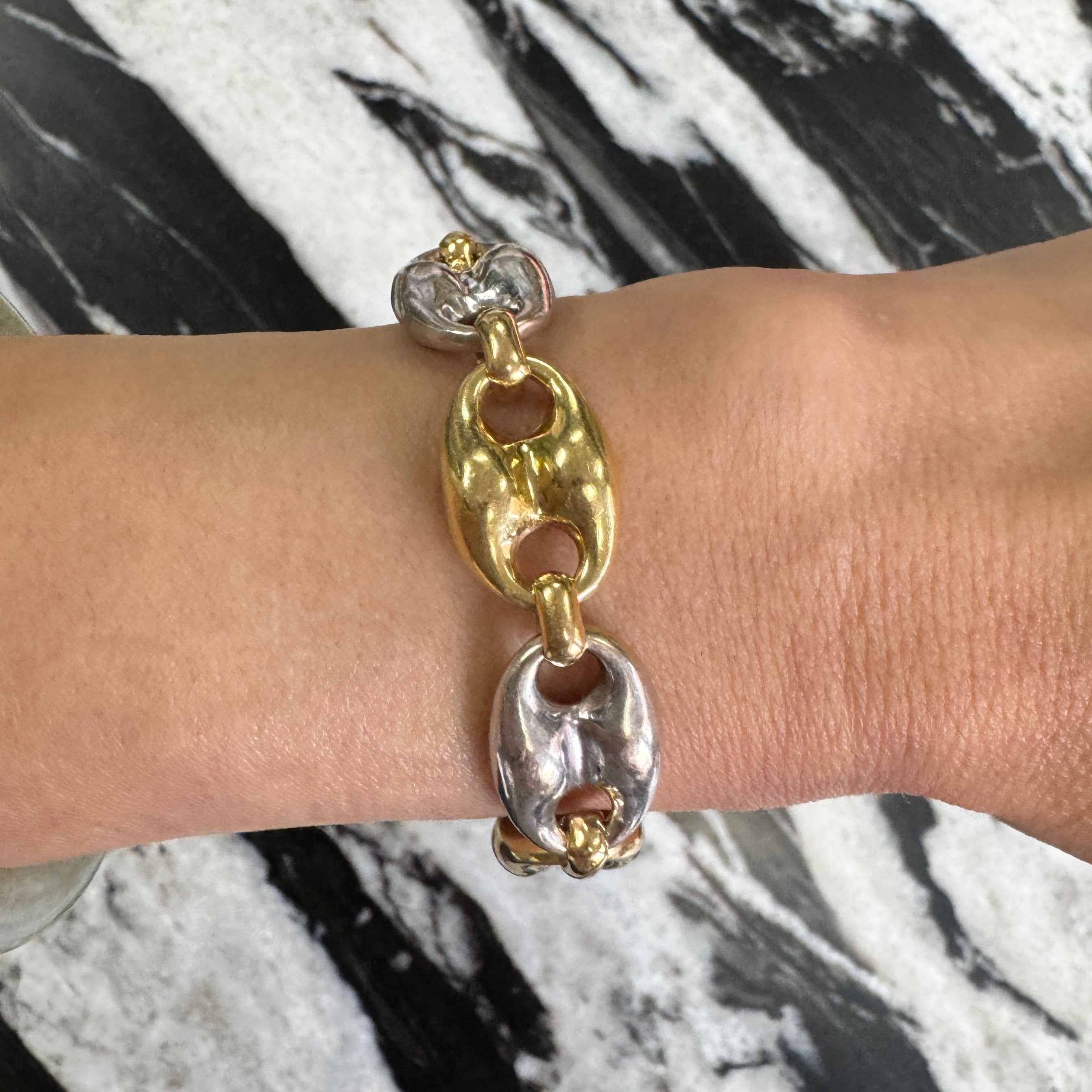 Bracelet with gold and silver chain links on a marble surface