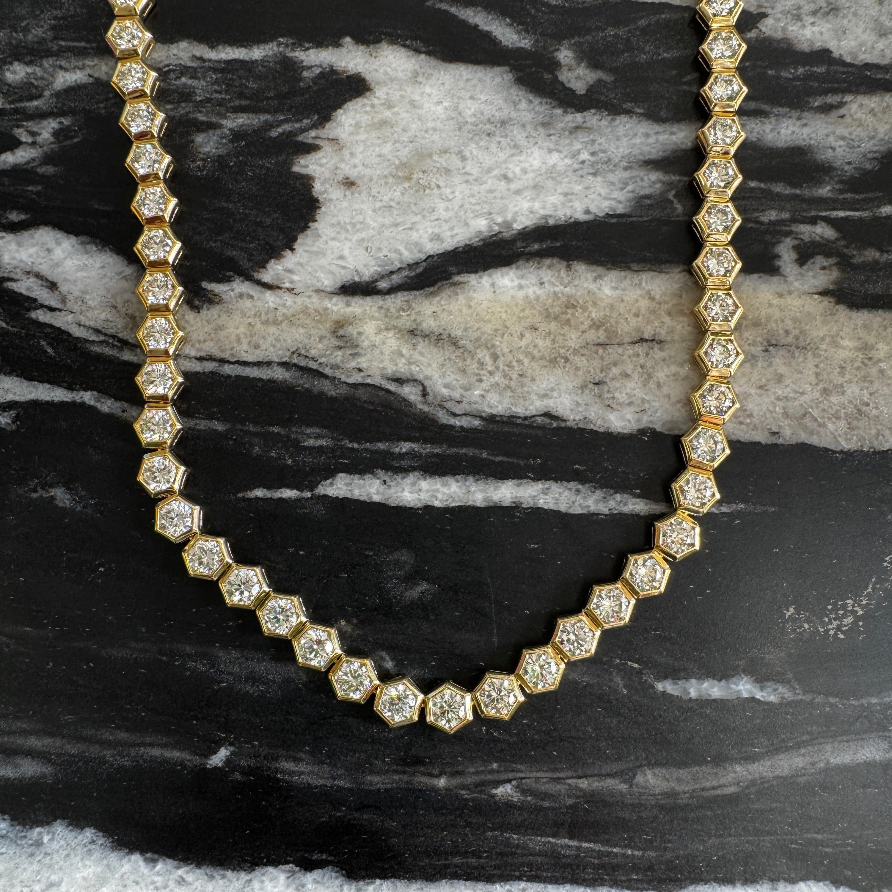 Gold necklace with diamonds on a black and white marble surface