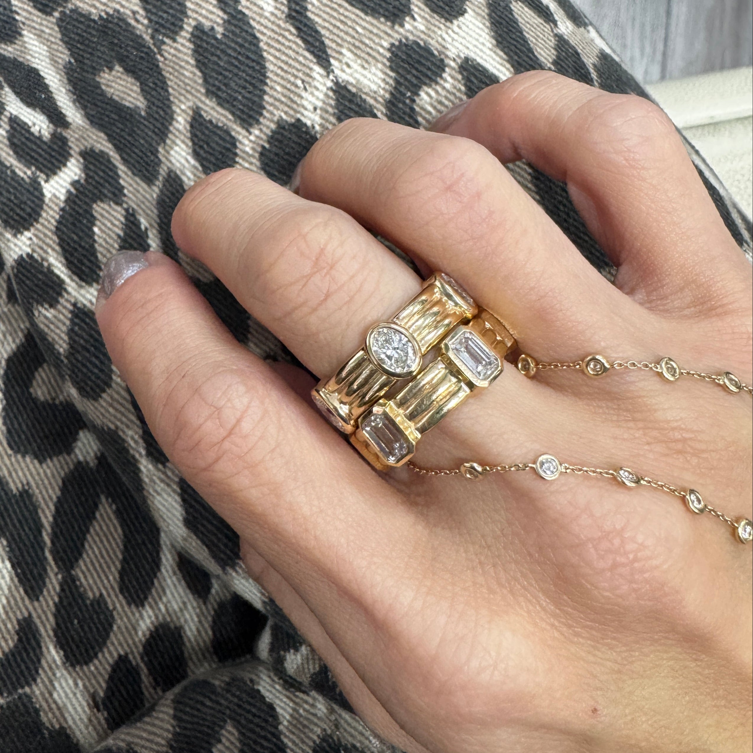 Hand wearing gold rings on a leopard print fabric background