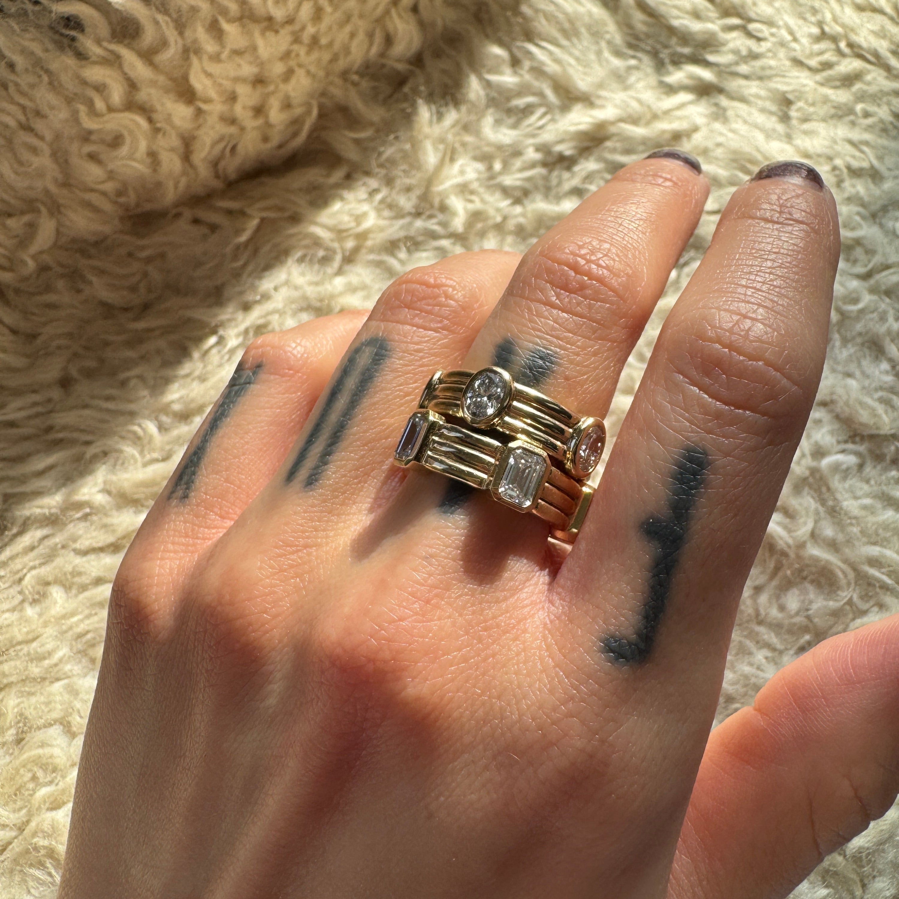 Hand wearing multiple rings with a textured beige background