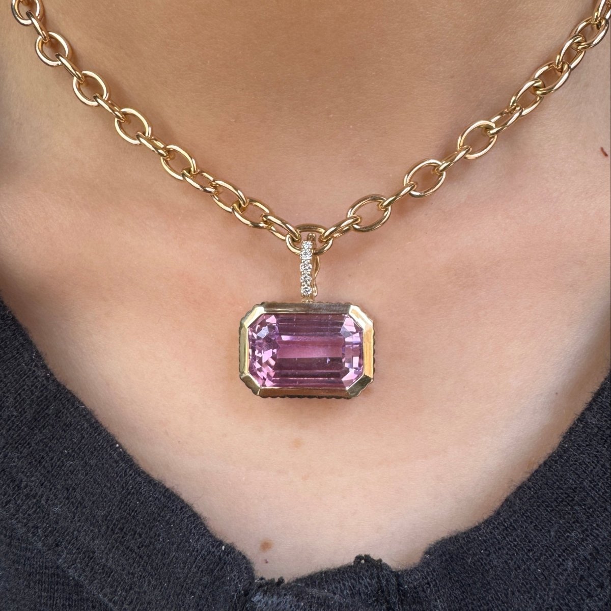 Person wearing a Gold pendant with an emerald-cut purple kunzite  and a diamond bail on a gold chain